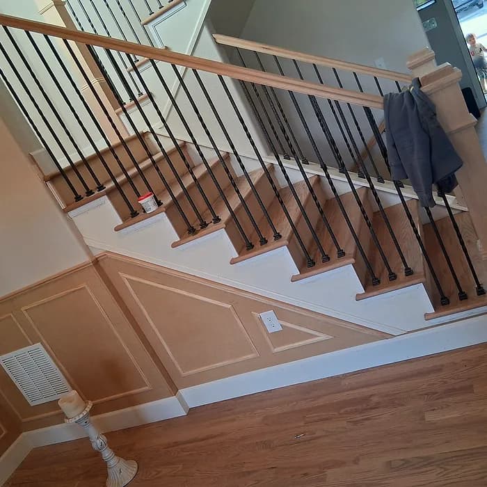 Hardwood staircase with iron balusters and raised-panel wainscoting
