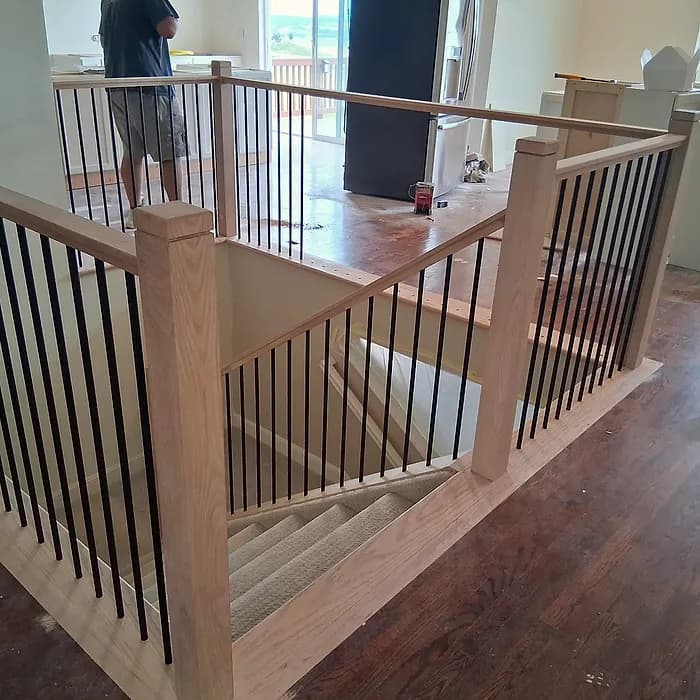 Stairwell railing with iron balusters and a wood handrail